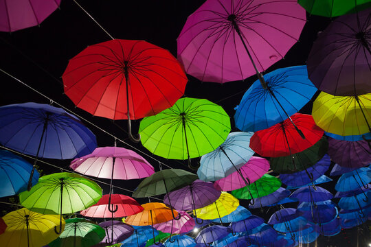 Red, green, blue, and purple umbrellas create a festive outdoor pattern, vibrant holiday decoration, creative background.