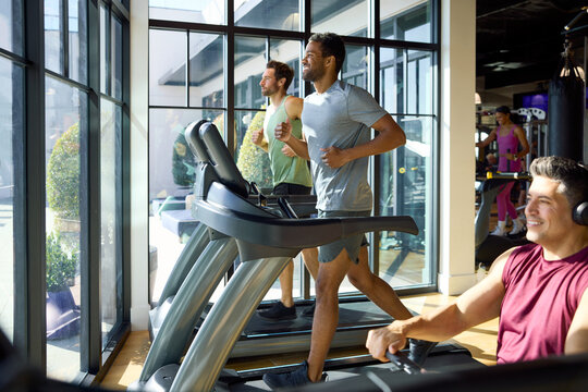 People running on treadmills d Rowing Machine in a bright gym. They move steadily, focused on their workout.  Office in-house gym