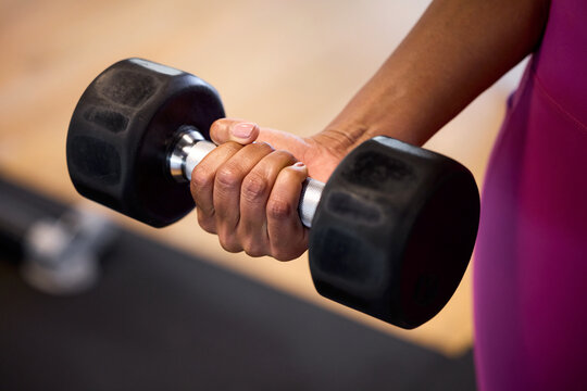 Hands gripping a dumbbell mid-lift. Muscles strain with focused effort. Determination fuels every rep. Office in-house gym