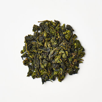 Dried green tea leaves on white background