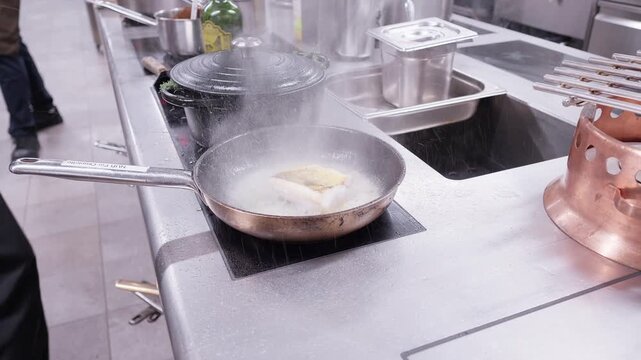 Cuisinier professionnel pr&eacute;parant un plat &agrave; la po&ecirc;le dans un restaurant