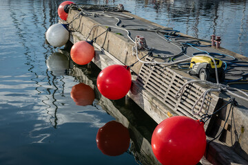 Wooden dock with mooring buoys reflected in calm harbor water © Vladimir Arndt
