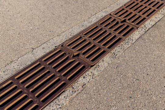 Brown metal storm drain grate on asphalt, construction site