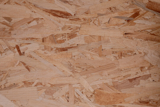 Close-up of an OSB panel surface made from compressed wood strands, creating a natural engineered wood texture for construction, architecture, carpentry and background concepts.