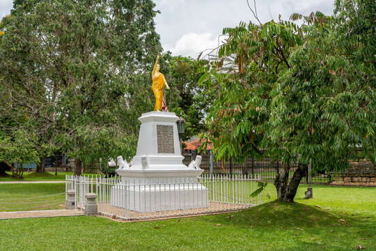 Standing monk statue monument on white pedestal in Temple of the Tooth grounds, Kandy, Sri Lanka. The Temple of the Sacred Tooth Relic, known locally as Sri Dalada Maligawa
