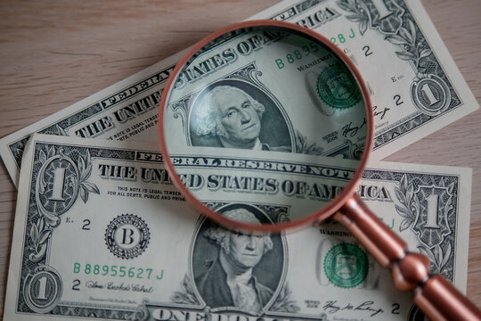 US Dollar Bills and Magnifying Glass Representing Currency, Finance, Banking, Wealth, Savings and Financial Analysis Concept