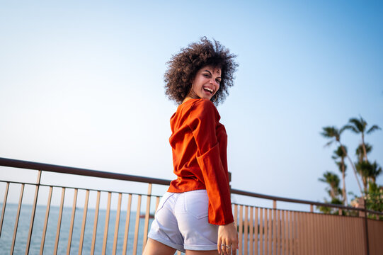 Young woman radiates the love of summer, travel, joyfully celebrating a fun holiday with arms raised