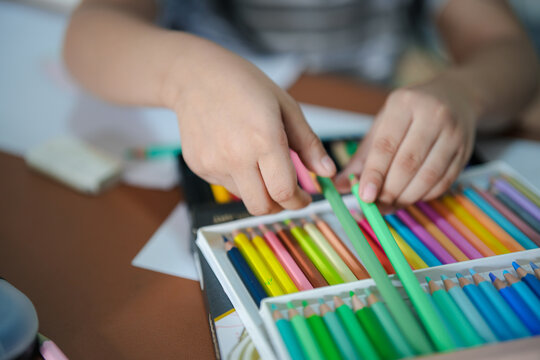 little girl learn to draw and paint with various pencil colour and white paper on wooden desk, family relationship concept, home school, holding pencil colour 