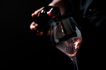 Naklejka premium Delicious red wine Merlot in glass from dark bottle — luxury celebration concept. Expert sommelier in apron serving alcoholic beverage. Premium restaurant hospitality, gourmet food pairing.