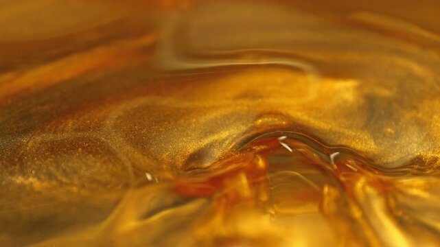 Super Slow Motion Shot of Swirling Golden Glittering Oil in Water at 1000fps.