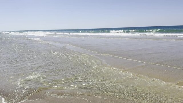 Netanya, Israel. A long sandy beach with a rocky coastline on a calm, windless day. A coastal cliff shows signs of landslide risk.