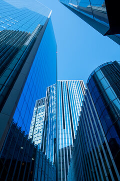 Looking up at blue glass office towers in The City of London England showing contemporary corporate architecture in a dense urban cluster