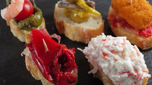 Assorted Spanish pintxos on bread with shrimp, tomato, anchovy, pepper, salad and croquette toppings.