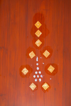 Close-up of an adult hand using a white marker to draw a decorative Thai-inspired symbol on a warm wooden surface, with plenty of copy space. Concept of traditional art, creativity, craftsmanship, cul