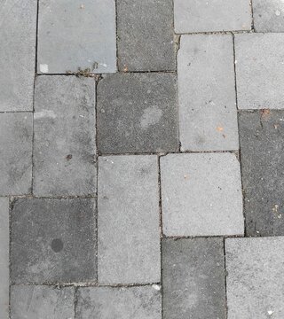 A pattern of rectangular grey stone pavers laid out on an outdoor pavement