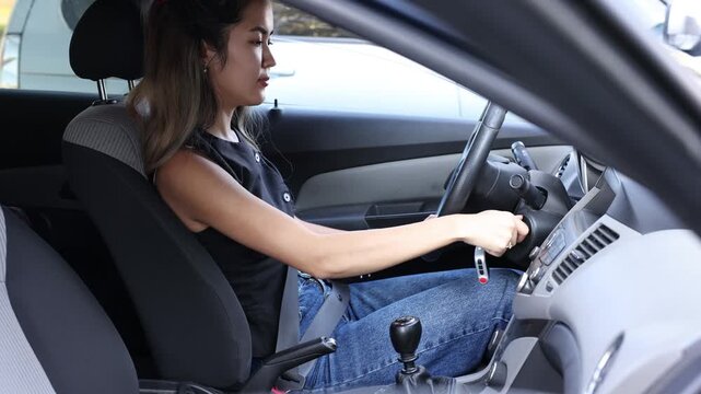 woman driving a car and changing hand position on the steering wheel while traveling on the road, interior, everyday transportation and mobility concept of automotive, driving school, insurance