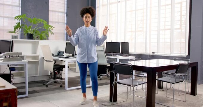 African American woman standing in modern office, smiling confidently at camera