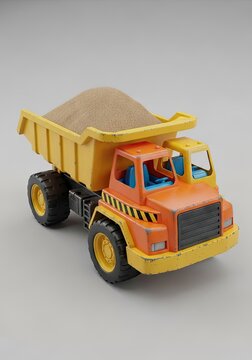 Orange and yellow toy dump truck with sand.
