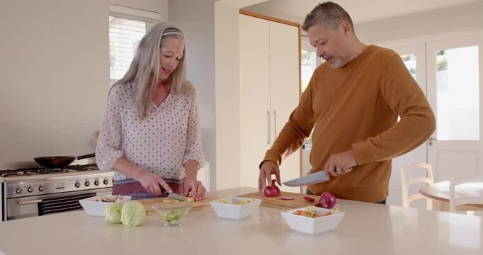 In kitchen, senior couple preparing fresh vegetables together, cooking at home happily