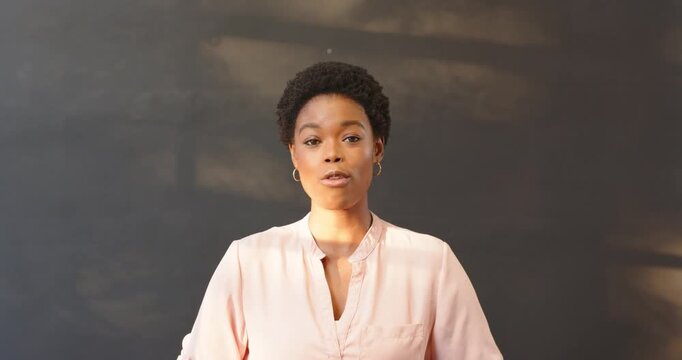 African American woman in pink blouse speaking confidently in professional setting