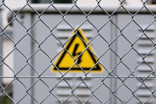 The Hazard Warning Sign Behind a Chain-Link Fence in Industrial Setting