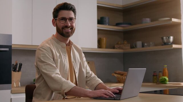 Happy Caucasian business man ordering food delivery on laptop in kitchen smiling looking at camera homeowner renter freelancer cheerful businessman shopping online using computer working remotely home