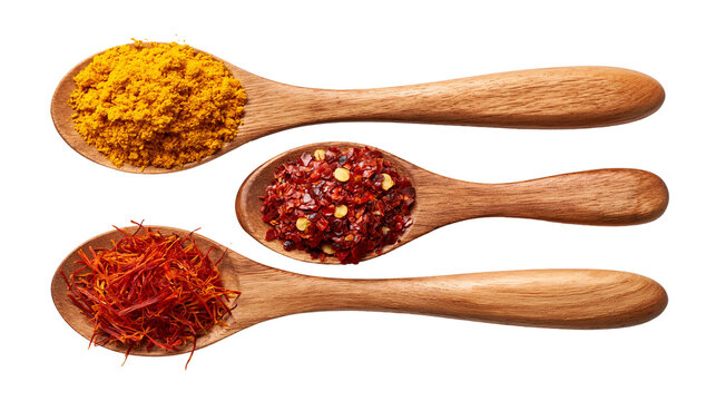 Turmeric powder red chili flakes, and saffron threads in wooden spoons