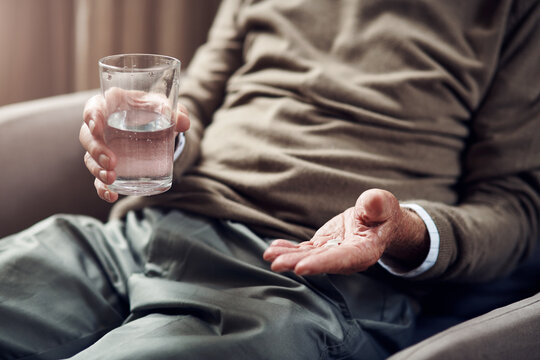 Senior, hands and water with pills for medication, healthcare treatment or antibiotic in home. Man, elderly person or patient with tablets, glass or mineral liquid for pharmaceutical remedy in house
