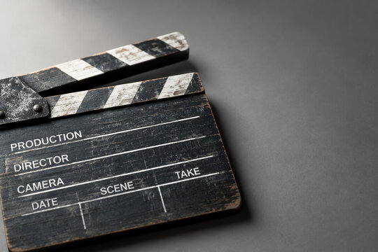 Weathered wooden film clapperboard on grey surface for filmmaking and cinema production concept