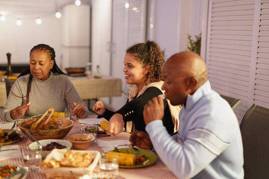 Happy african family eating dinner together during night time - People lifestyle, food and bonding concept