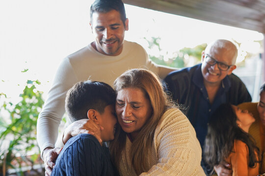 Latin american family having tender moment together at house patio - Grandmother hugging her grandson - Bonding, love and multi generational people concept
