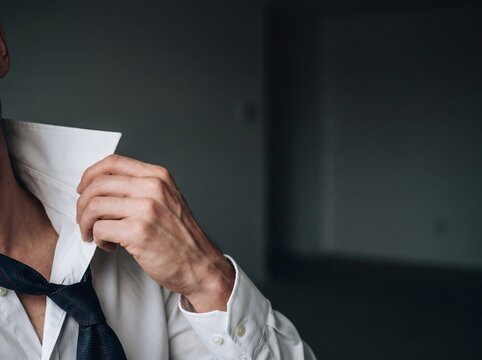 Close up of exhausted businessman loosening tie and unbuttoning white shirt for burnout and relief concept