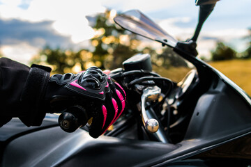 Biker's hand wearing pink and black protective glove gripping motorcycle handlebar © Ivi - Powerlightss