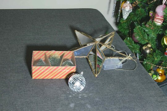 Decor items are arranged on a table near a Christmas tree during the holiday season