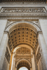 Low angle view of a grand arched entrance featuring decorative stonework, a richly detailed ceiling and classical architectural ornamentation. © Anastasia