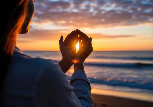 Woman cupping sunset light at beach for hope