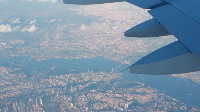 An aerial 4K 60fps shot from an airplane window captures a panoramic view of Istanbul, the Bosphorus strait, and the 15 Temmuz Sehitler Bridge from above.
