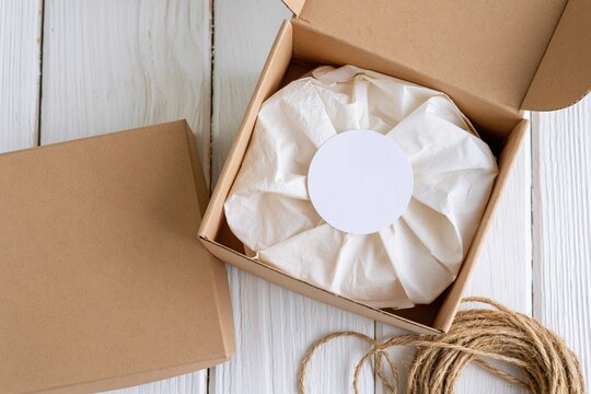 The Gift Box Among White Wrappings in Cardboard Box on Wooden Surface