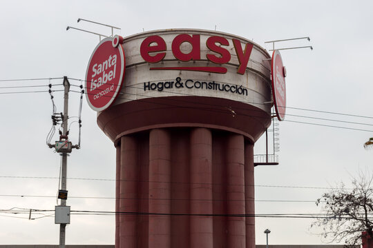 A tall cylindrical water tower in Santiago, Chile displays large commercial signage for Easy, Santa Isabel, and Cencosud against an overcast sky