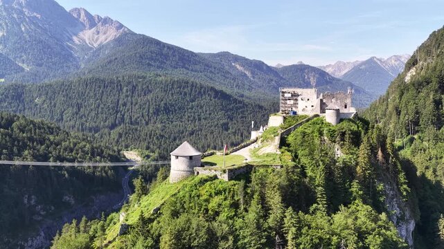 Distant view of Ehrenberg Castle near Reutte, Austria, positioned high above the forested valley with rugged Tyrolean mountain peaks extending across the horizon.