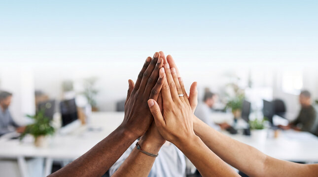 Diverse team high-fiving hands together in office signifying success and unity