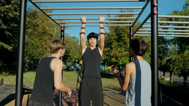 Youth group doing pull ups on monkey bars during outdoor team training.