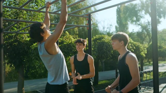 Young guys celebrating after intense pull ups at the fitness ground.