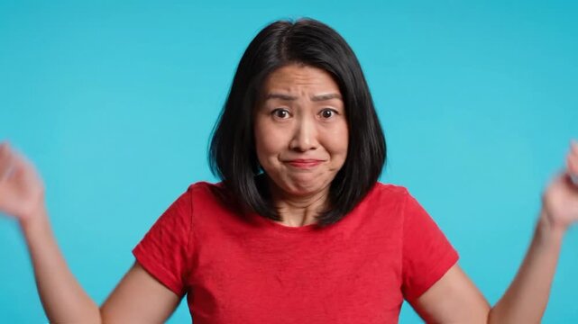 Clueless woman portrait showing confusion with hands raised in front of blue background