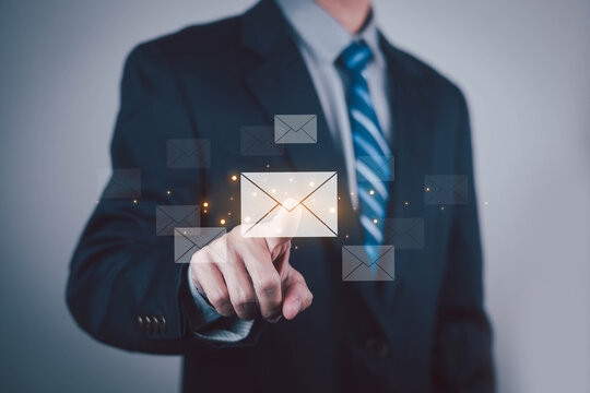Businessman touching a glowing email icon with floating messages, symbolizing digital communication email marketing customer engagement online messaging corporate technology and business connectivity.