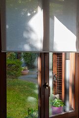 Obraz premium Cozy Sunny Green Garden View Through Window with Traditional Wooden Shutters