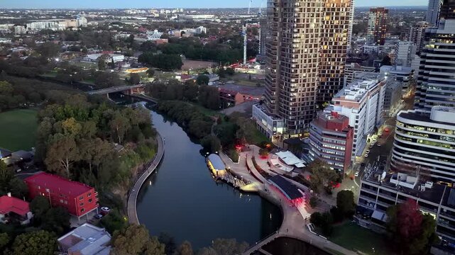 No sky aerial view of modern urban architecture on Parramatta river waterfront at sunset.