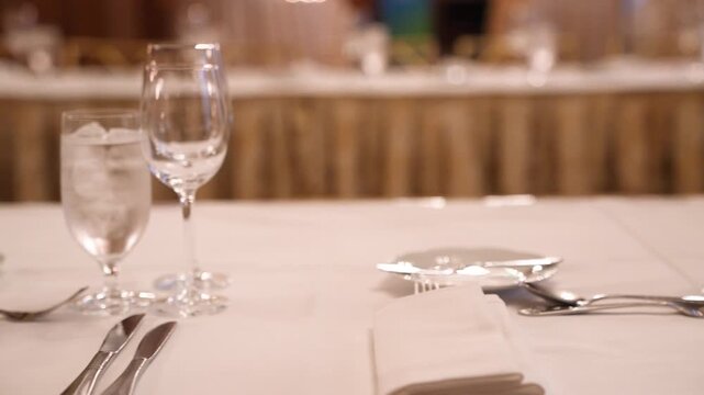 Cinematic footage of an elegant banquet table setting with crystal glassware, silverware, and a microphone, perfect for formal events and weddings.
