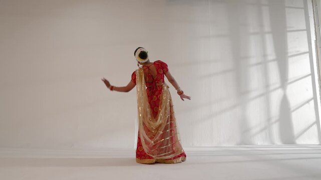 A woman is gracefully performing an Indian classical dance indoors