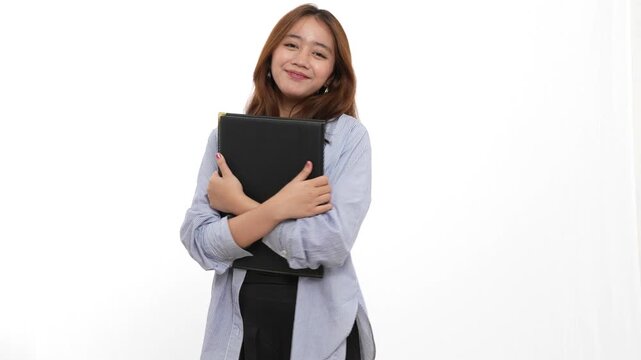 Young woman with brown hair holding a black file folder standing on a plain white studio